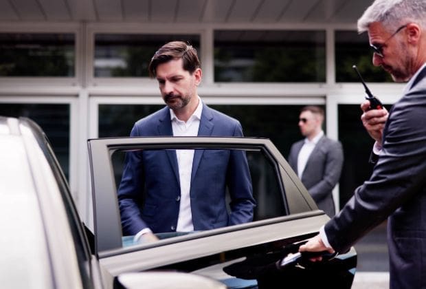 Man entering a car with security detail
